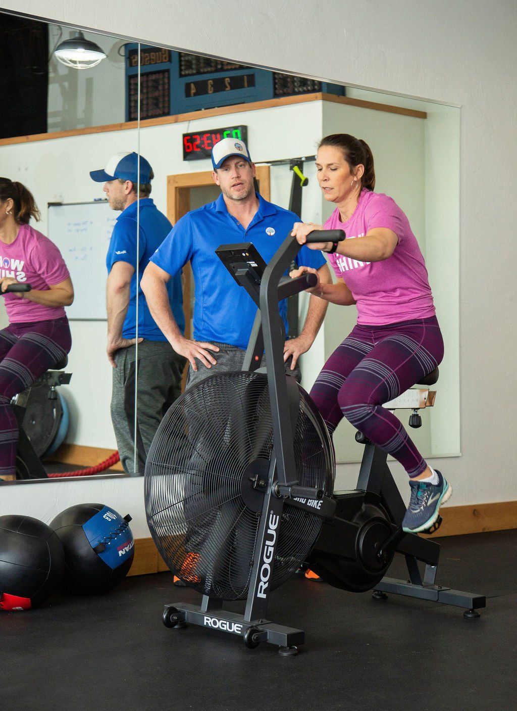 A man and a woman are riding an exercise bike in a gym.