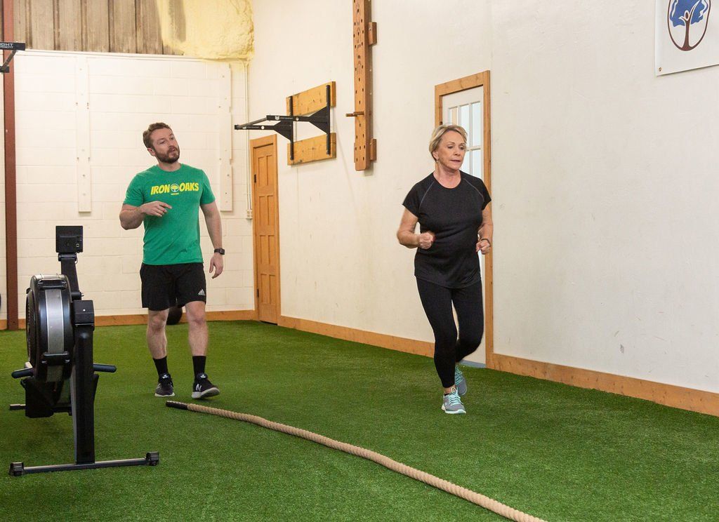 A man and a woman are running on a rope in a gym.