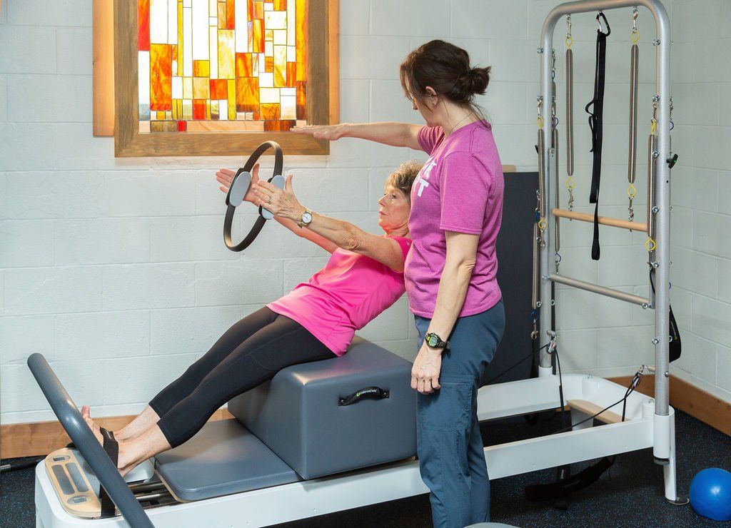 A woman is teaching a woman how to do pilates on a pilates machine.