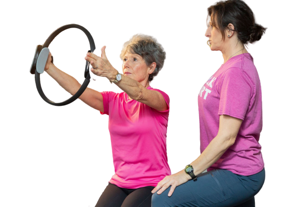 Two women are doing exercises with a pilates ring