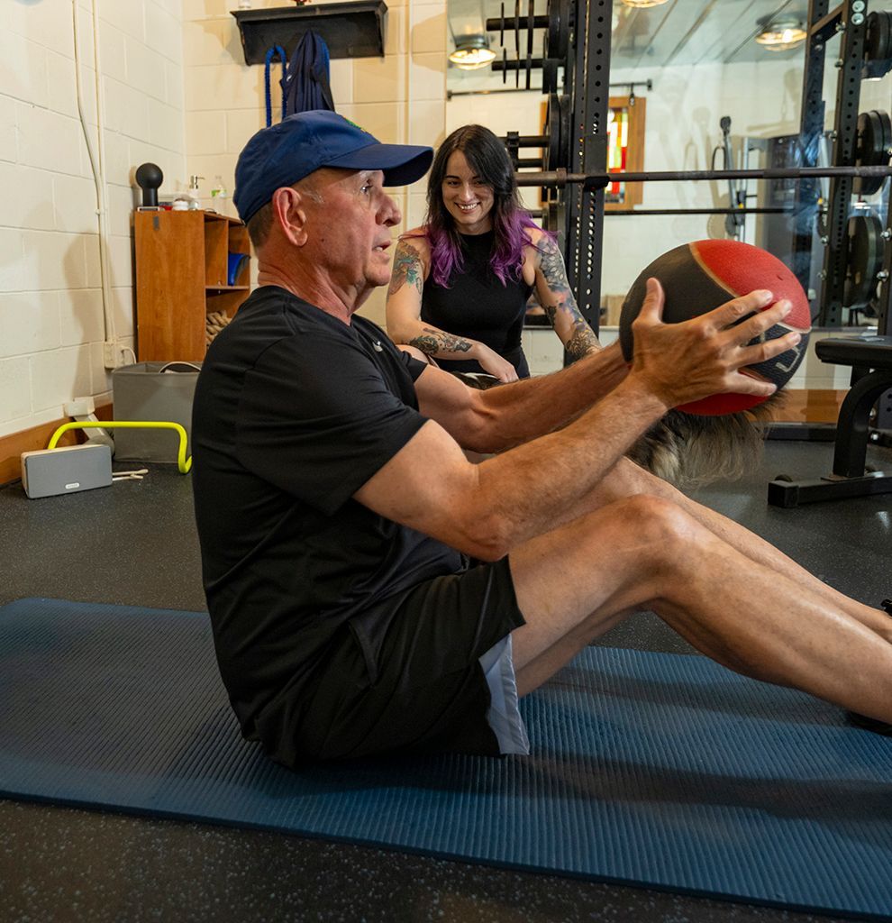 A man in a blue shirt is smiling while holding a trx strap.
