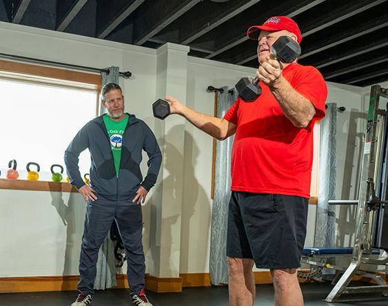 A man in a green shirt is helping a woman sit on the floor