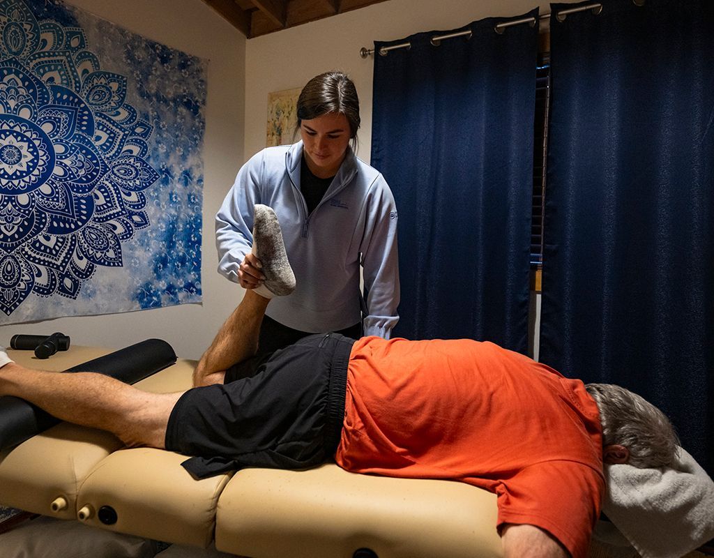 A man in a green shirt is talking to a woman who is lifting dumbbells