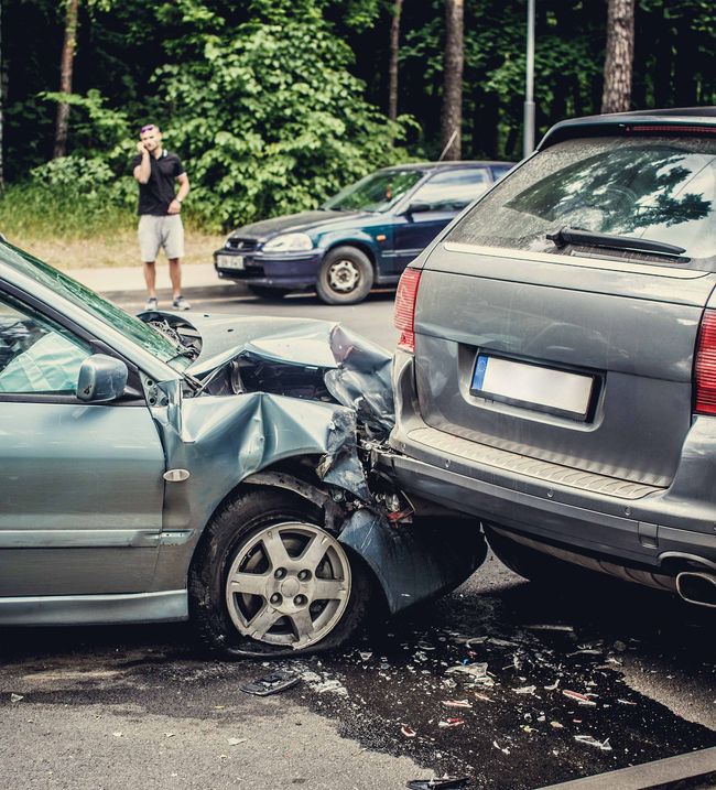 A man is taking a picture of a car accident.