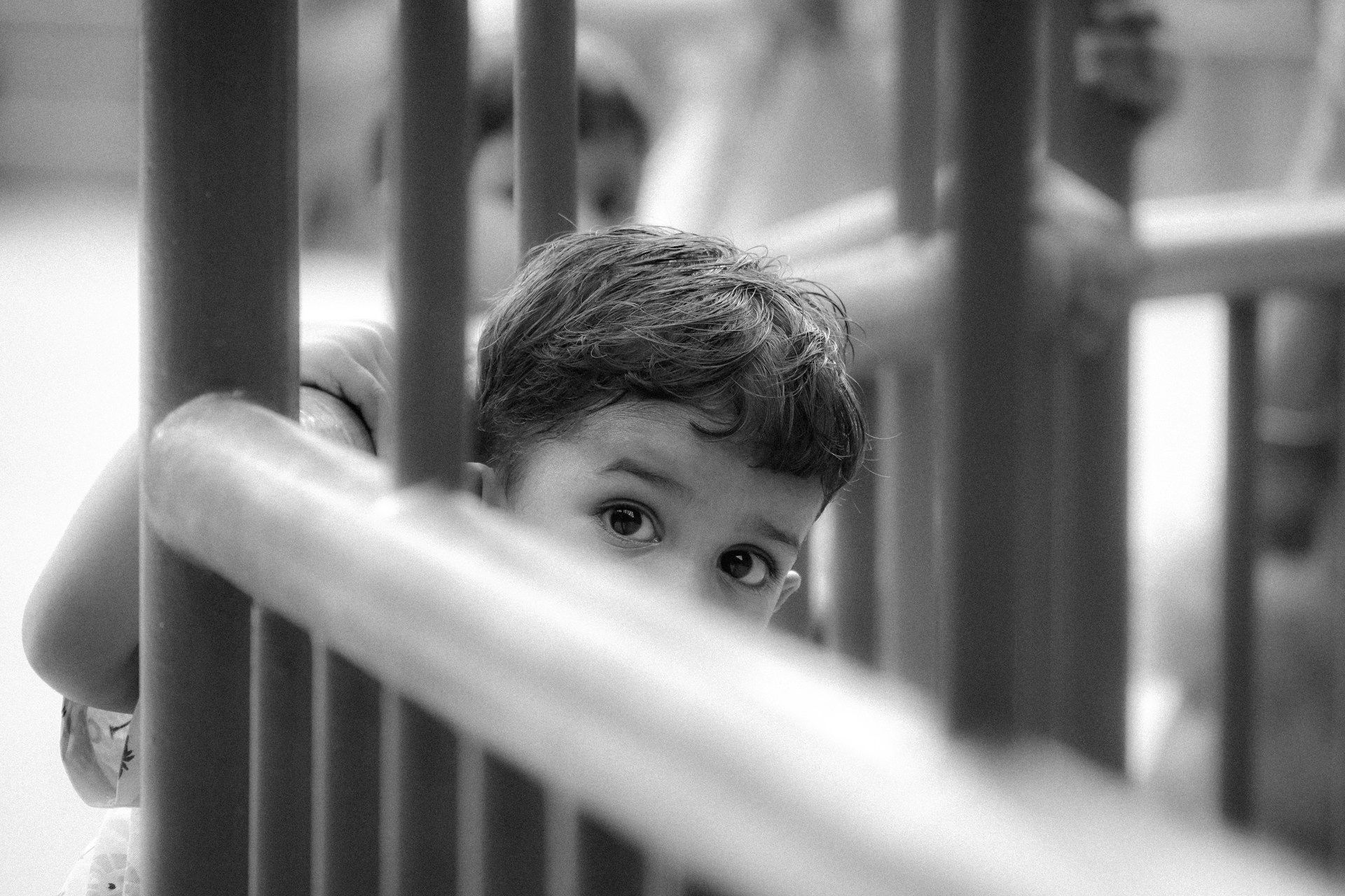 A black and white photo of a child peeking over a railing.
