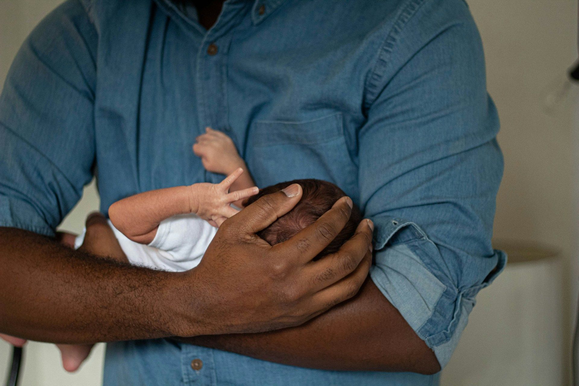 A man is holding a newborn baby in his arms.
