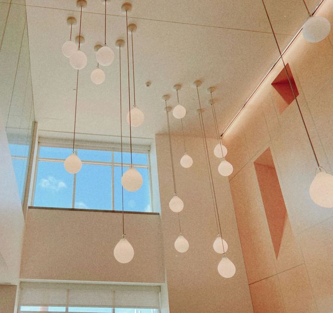 Modern atrium with hanging white globe lights and a blue skylight window.