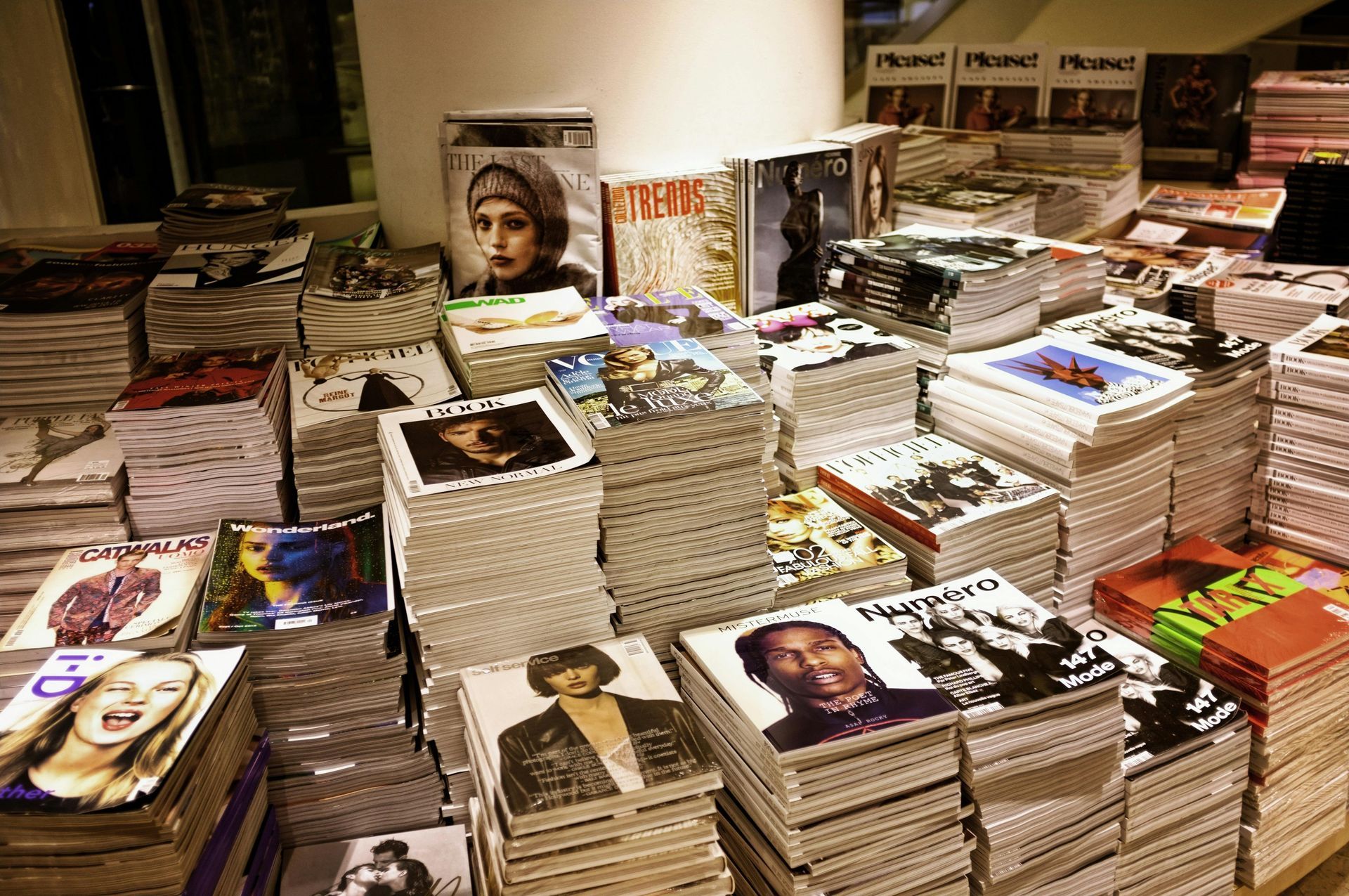 Stacks of CDs and magazines on a counter in a store, with covers featuring people.