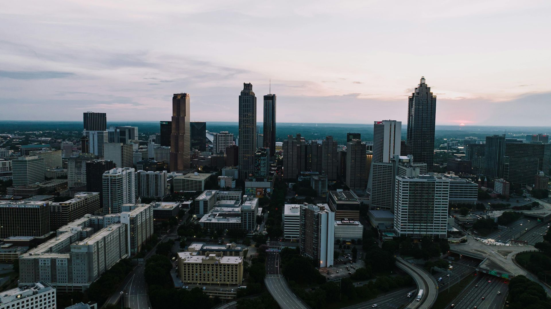 Atlanta skyline at dusk, with tall buildings silhouetted against a cloudy sky.