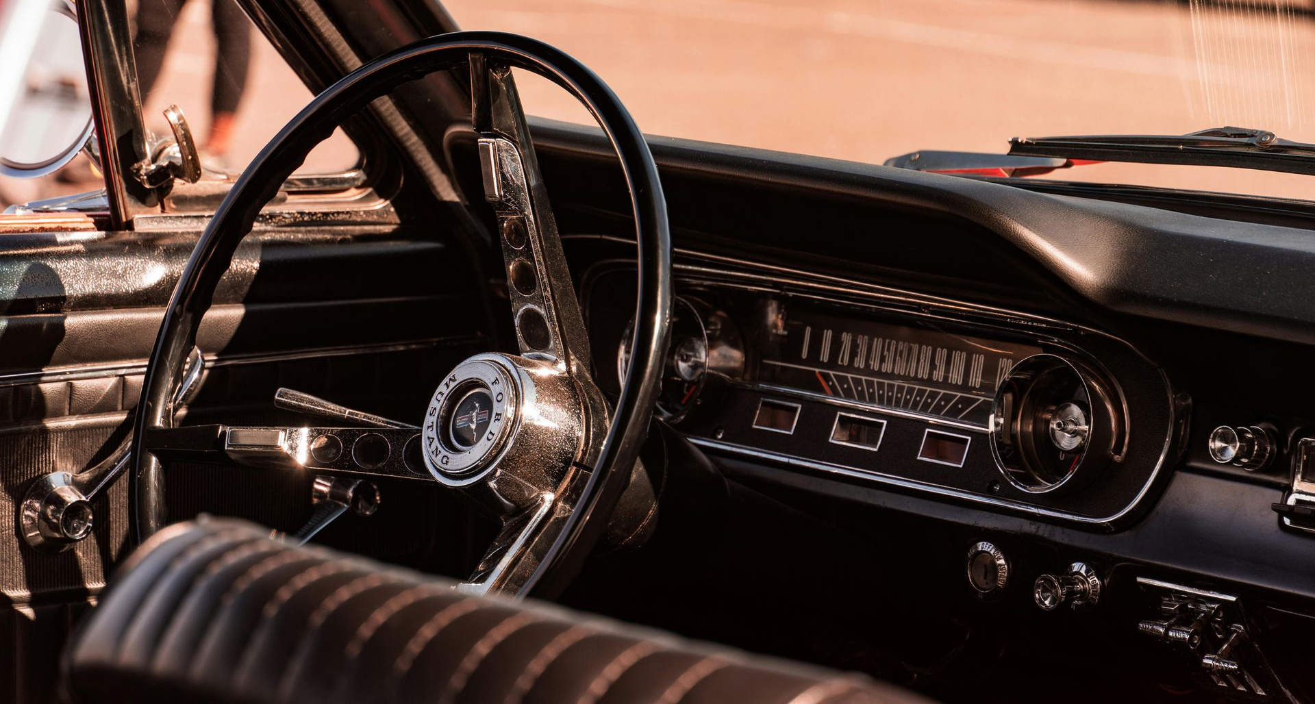 Paintbrush mixing dark brown paint on a wooden artist's palette with various colorful paint splotches.
