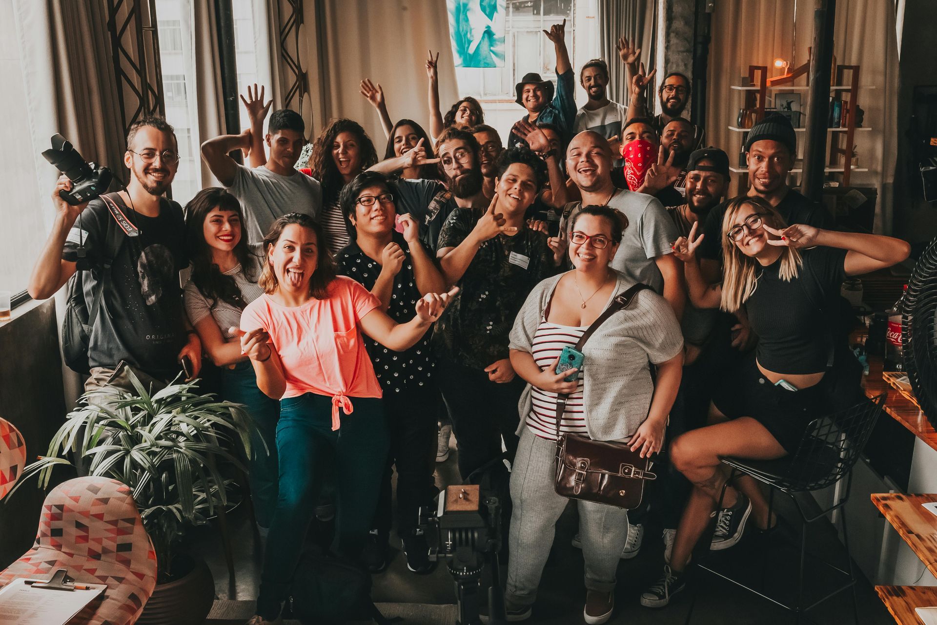 Large group of diverse people smiling, posing together in a room with natural light.