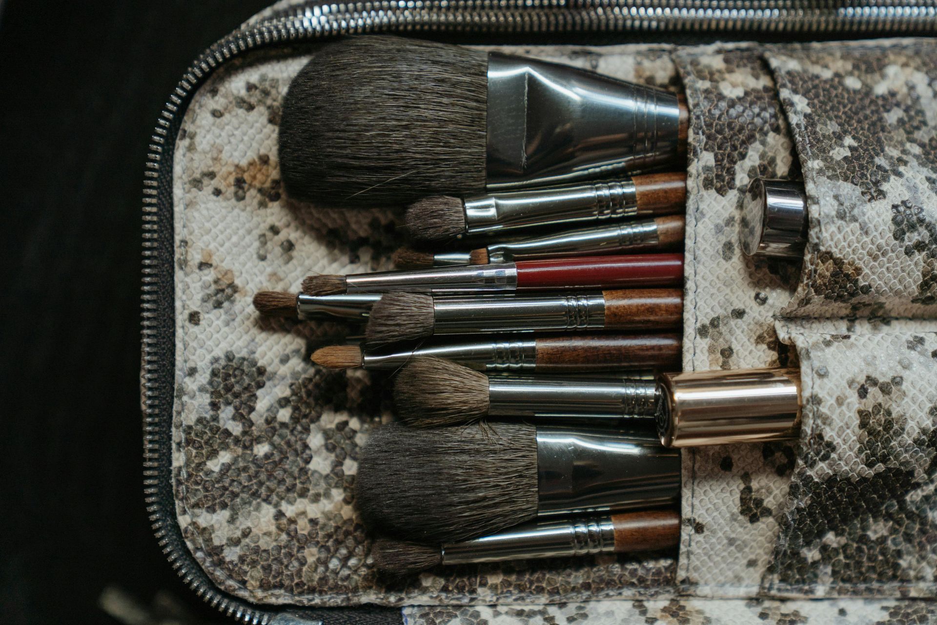 Makeup brushes in a camouflage-patterned case; various sizes and shapes, some with metal handles.