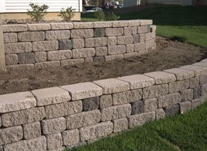 A brick wall with a planter in the middle of it in front of a house.