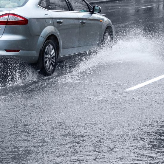 Grey Ford Mondeo driving on very wet road
