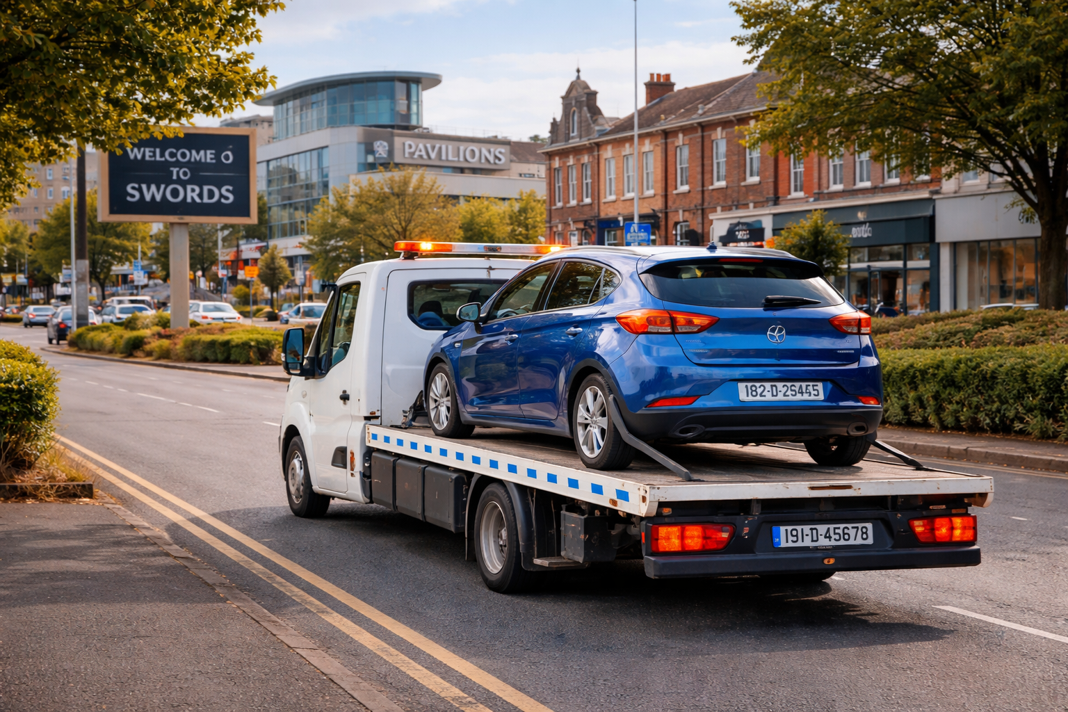 white tow truck carrying blue car with Dublin plates in Swords