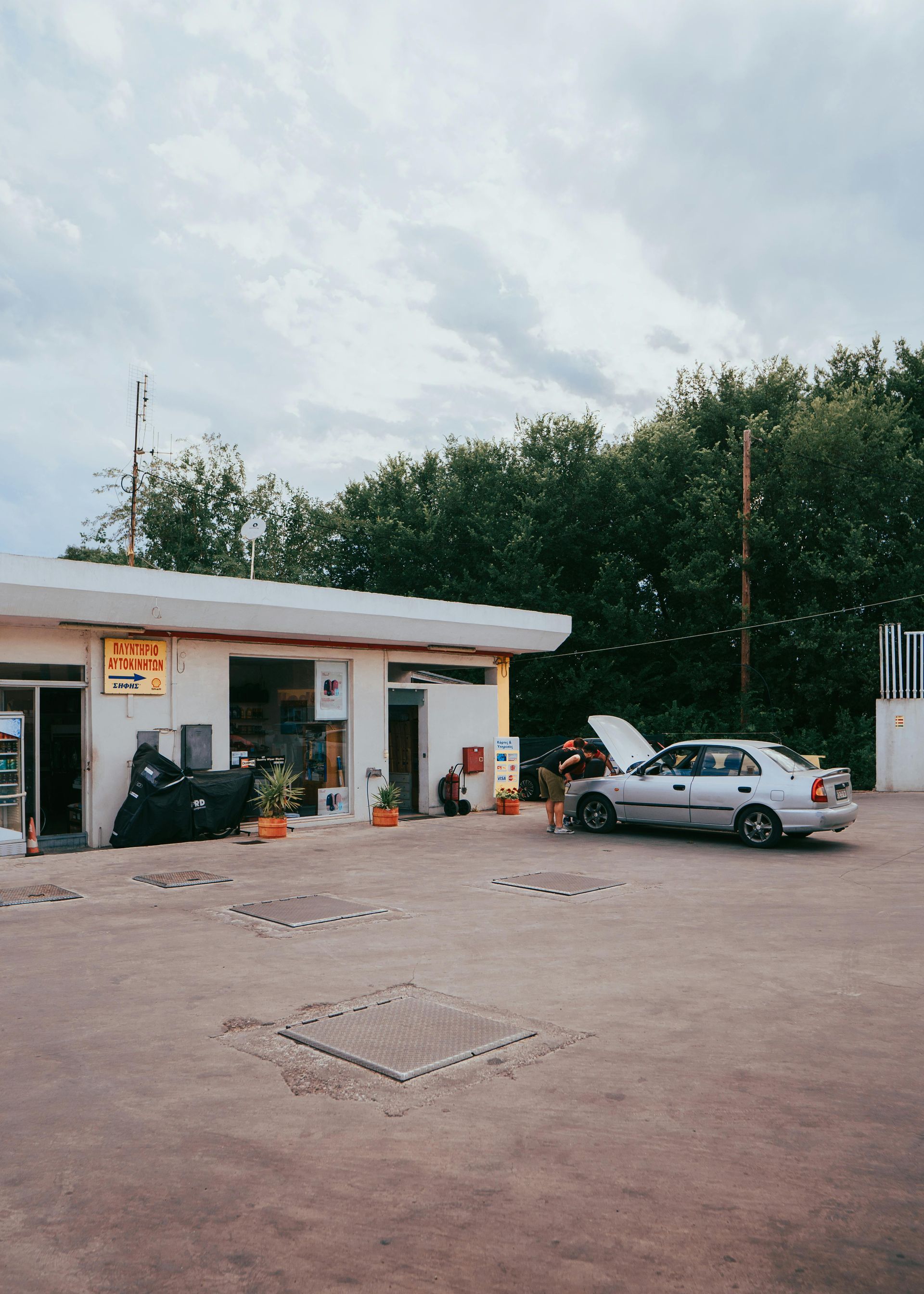 grey sky, green hedges broken down car