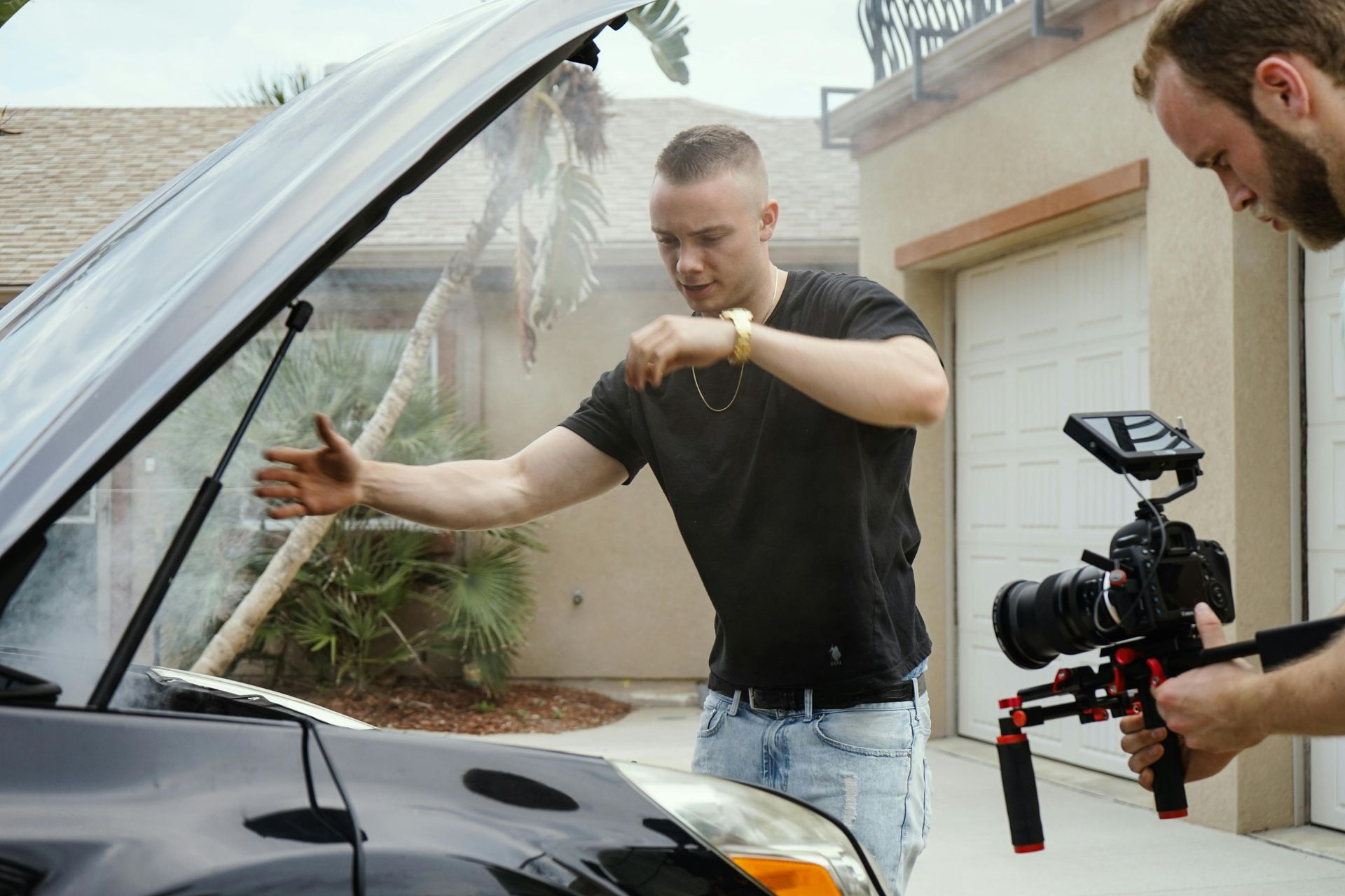 young mansweeping smoke away from the car engine with his arms