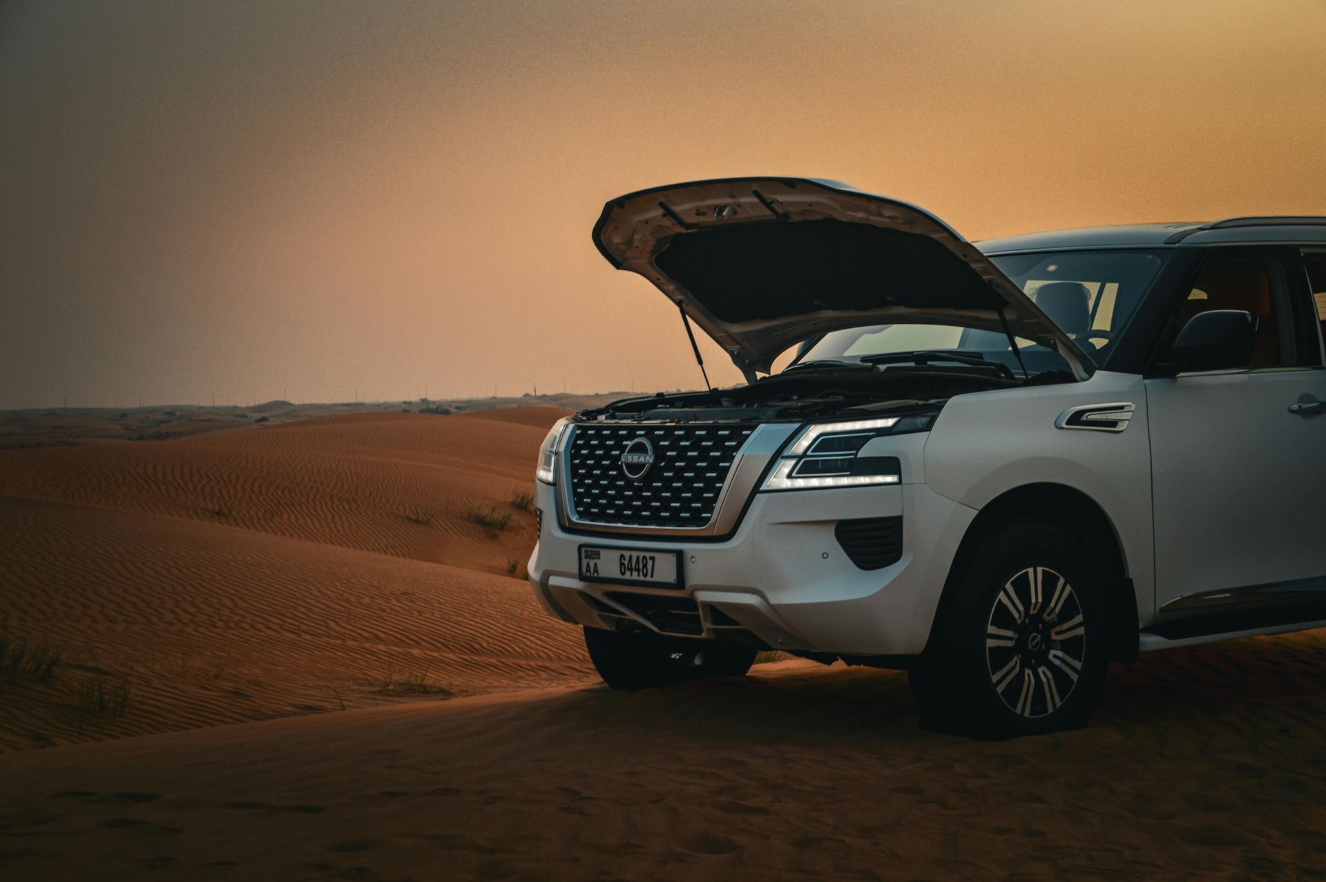 white nissan 4x4 with the bonnet up in the desert