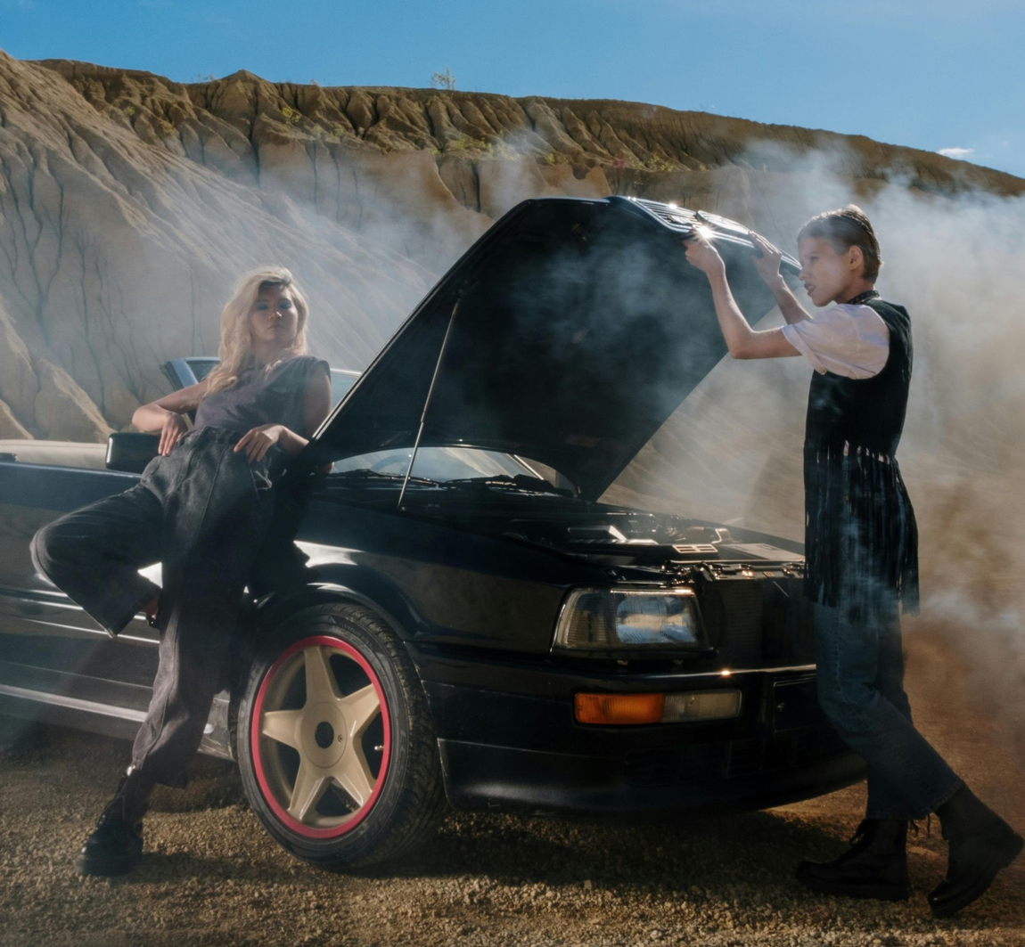 Two woman outside a broken down car outside
