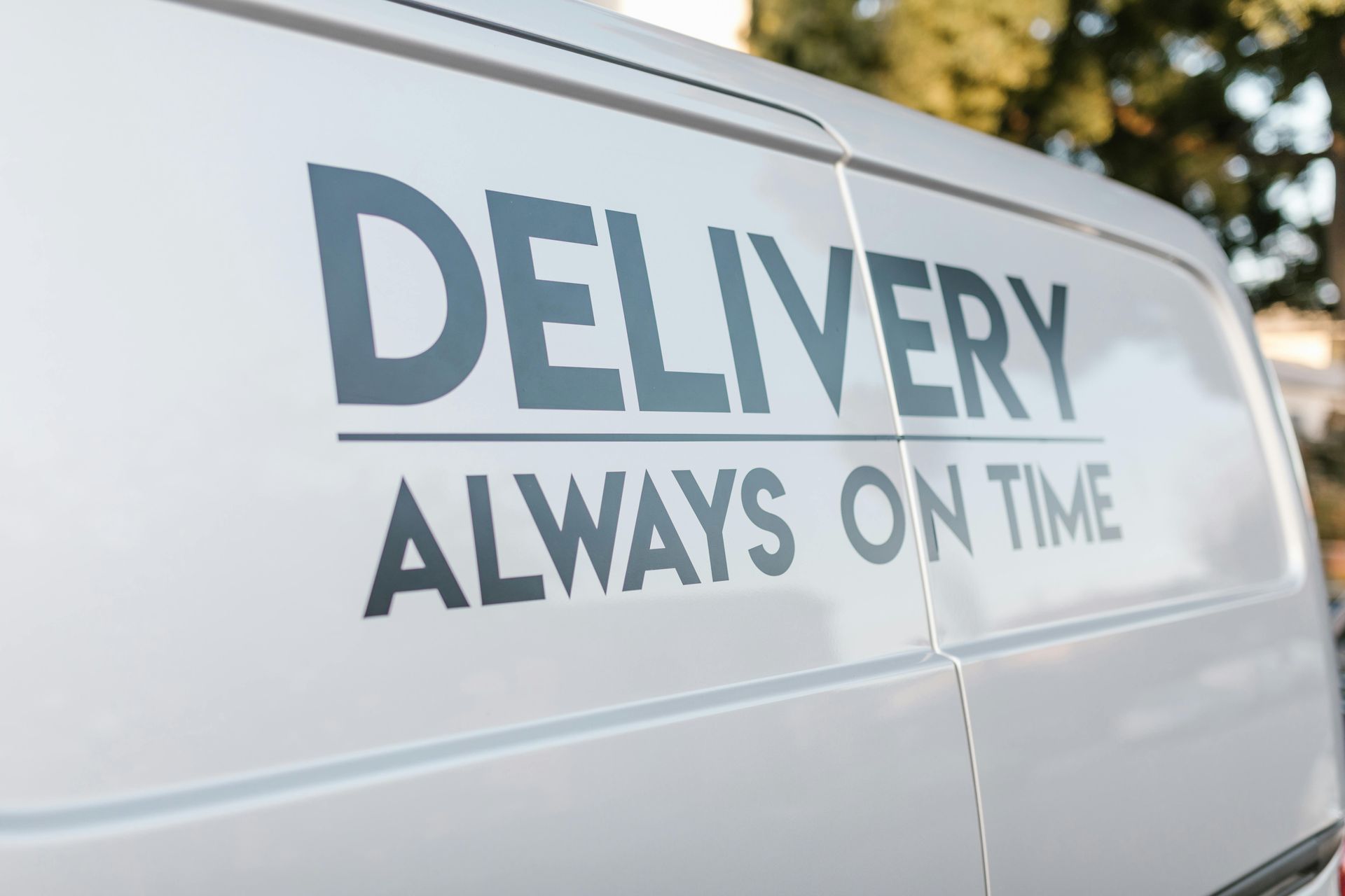 White van with the words Delivery Always On Time on the side of the van