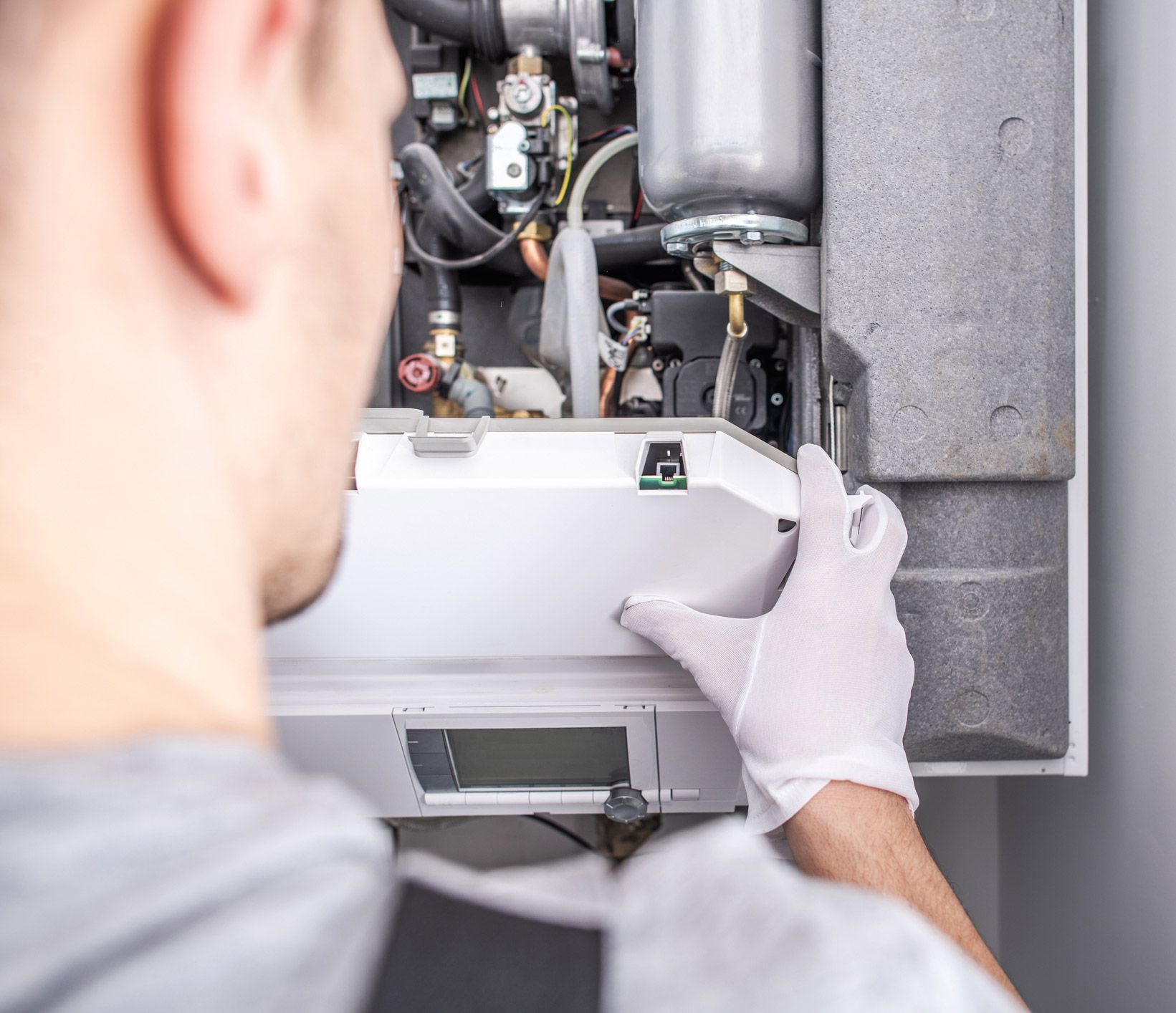 Man in gloves opening the cover of a boiler.