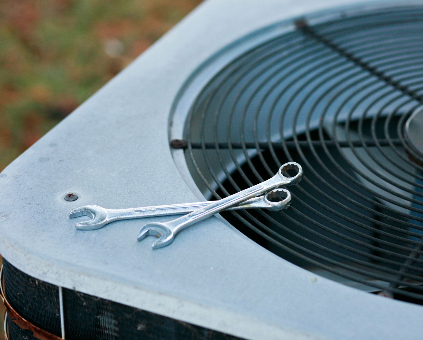 Two wrenches resting on an air conditioning unit.