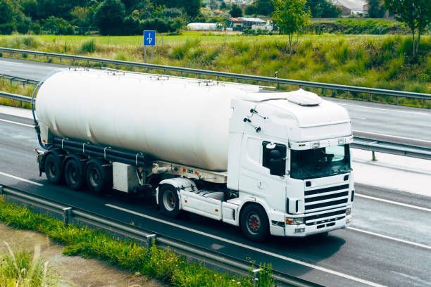 White tanker truck on highway, transporting goods.