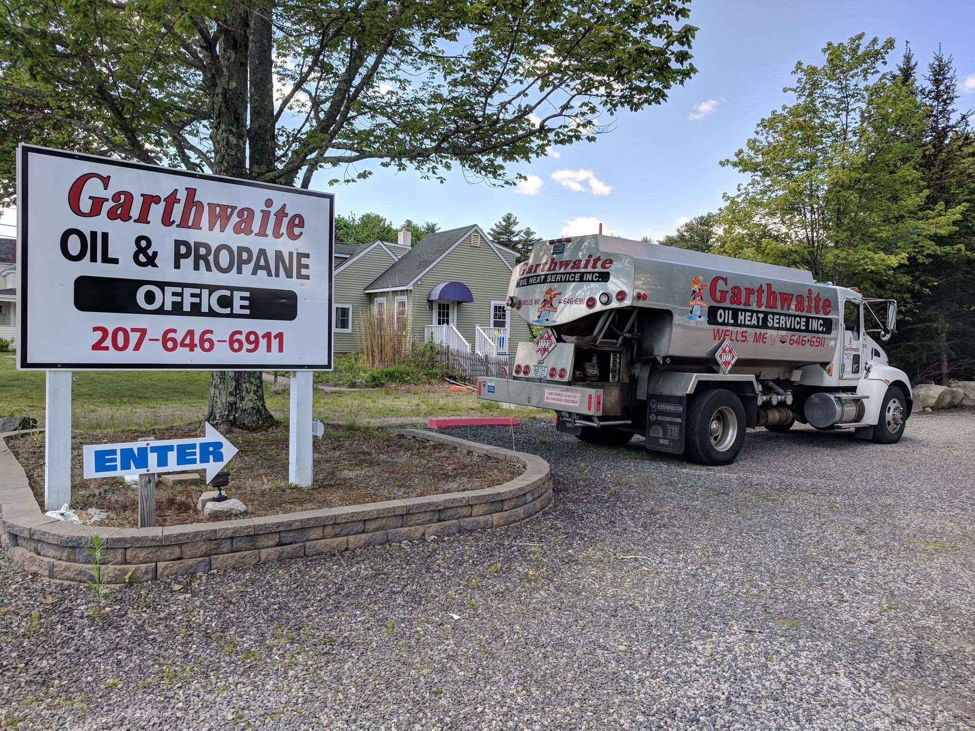 Red and silver tanker truck parked outdoors, near a building with palm trees.