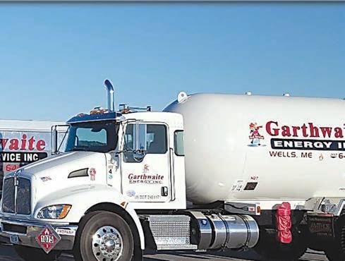 White propane truck on a highway, carrying a large cylindrical tank.