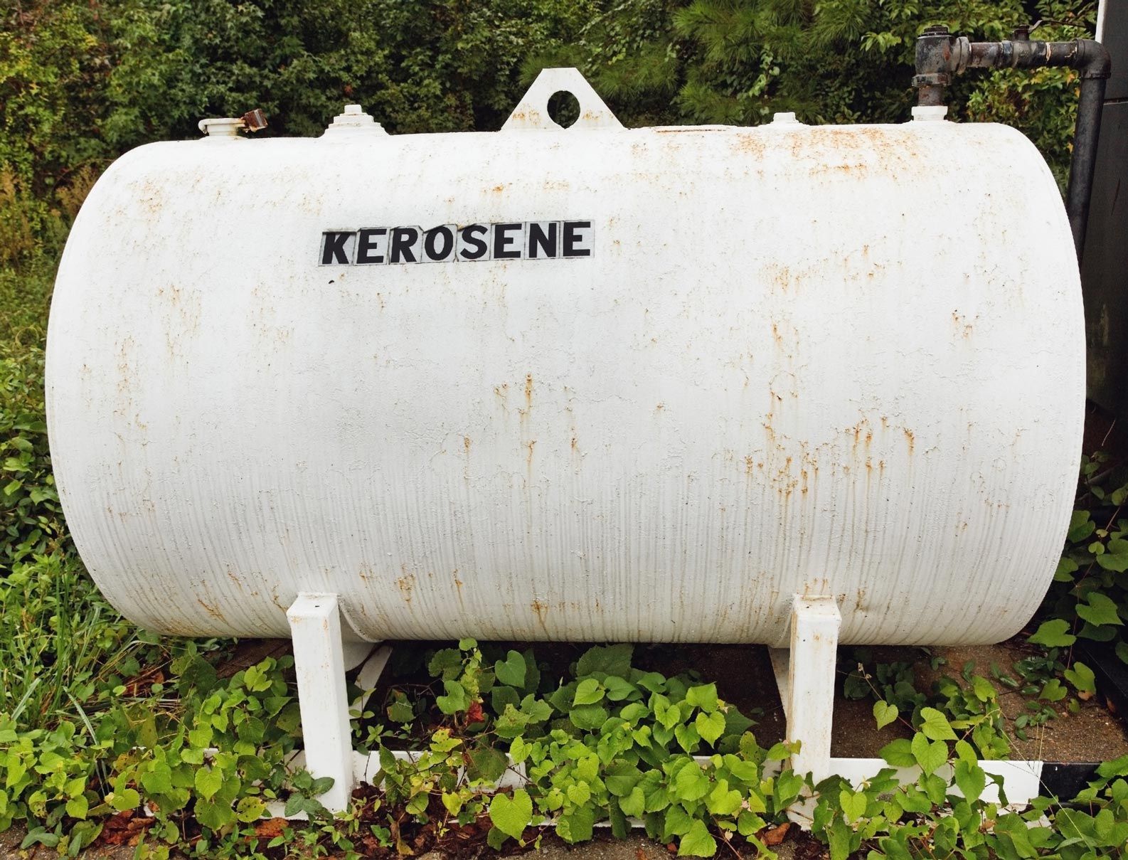 White kerosene storage tank outdoors with 'KEROSENE' text.