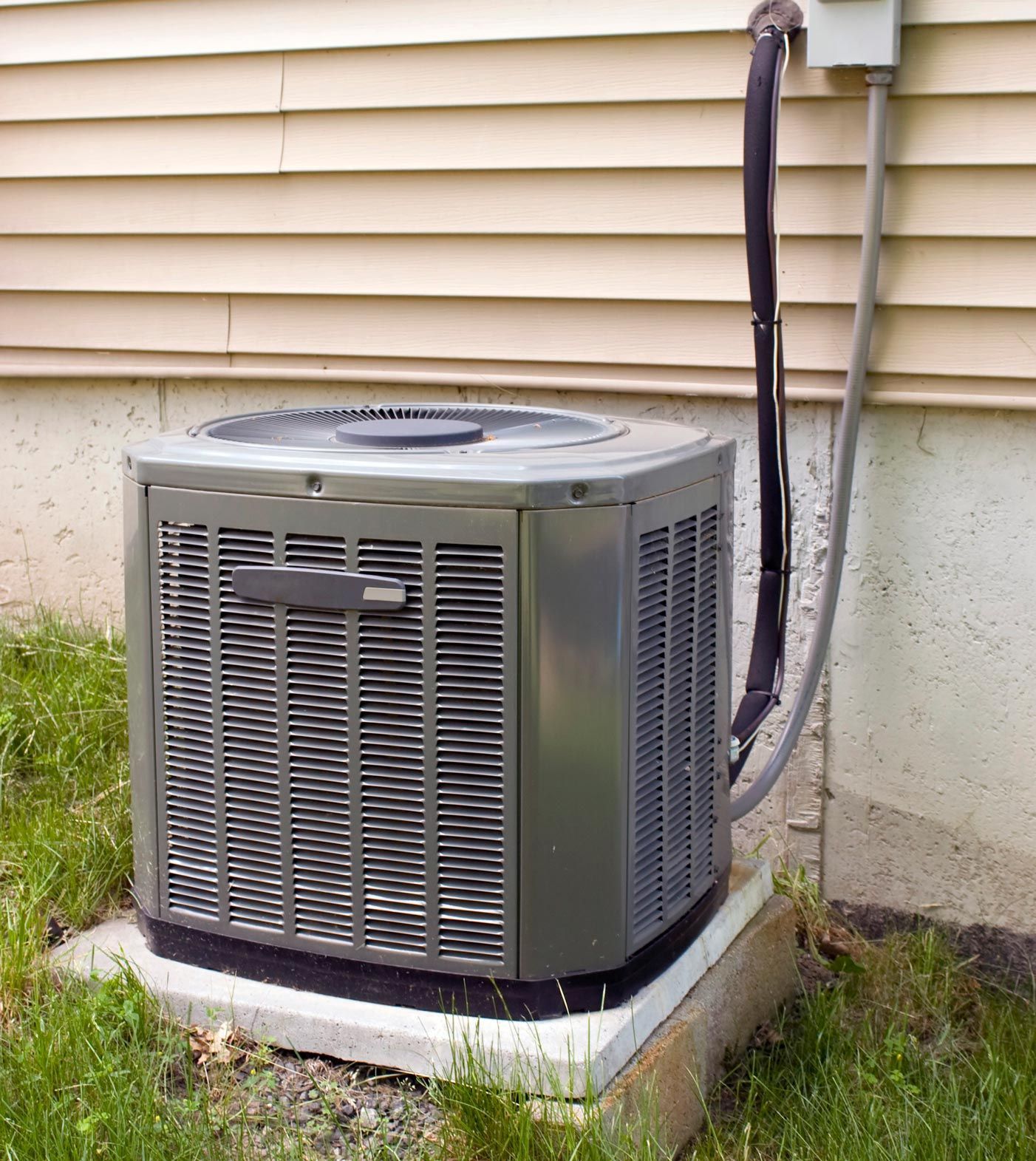 Air conditioning unit outside a house; gray metal with a fan.