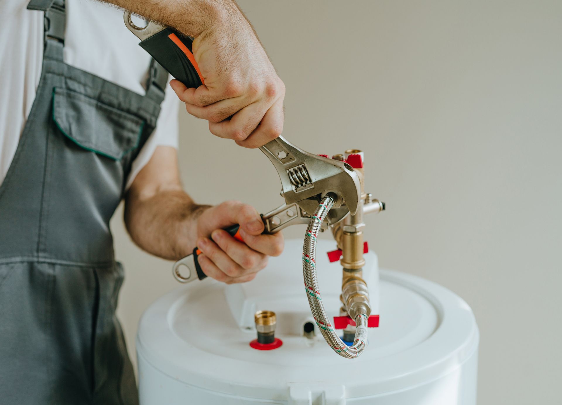 Plumber using a wrench to tighten a fitting on a hot water heater.