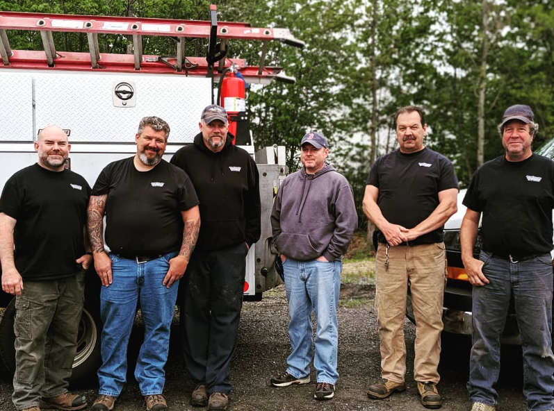 A shiny tanker truck hauling liquid fuel down a highway under a clear blue sky.