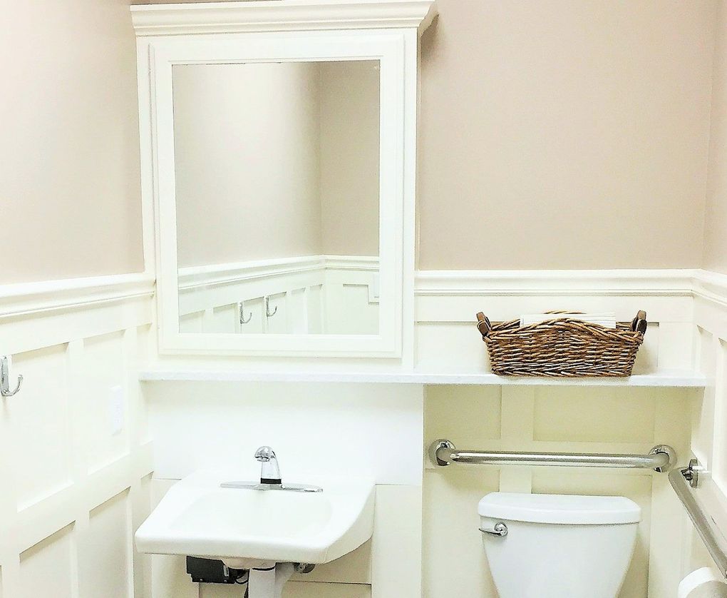 A bathroom with a toilet a sink and a mirror