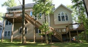 A large house with a large deck and stairs surrounded by trees.