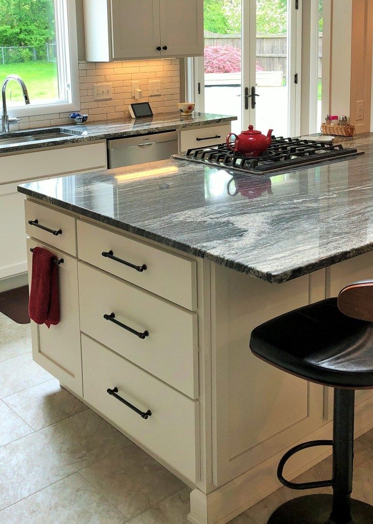 A kitchen with granite counter tops and white cabinets