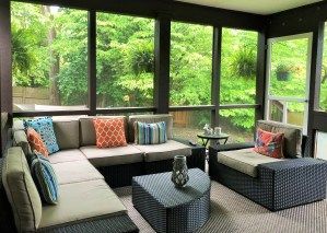 A screened in porch with a couch , chairs , and a table.