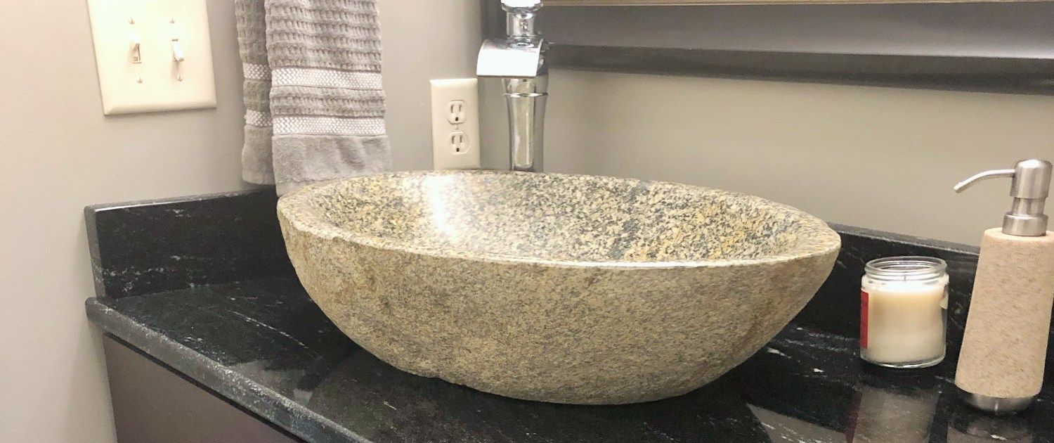 A bathroom sink is sitting on top of a black counter.