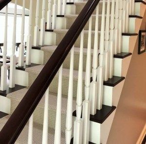 A close up of a staircase with white railings and a carpeted staircase.