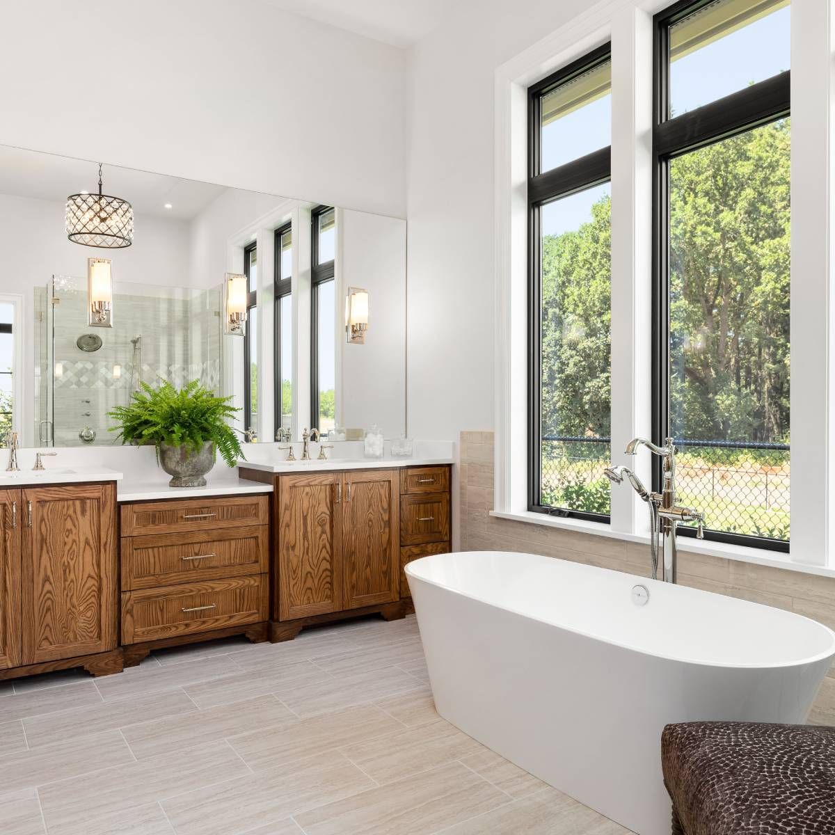 A bathroom with a tub , sinks , mirrors and windows.