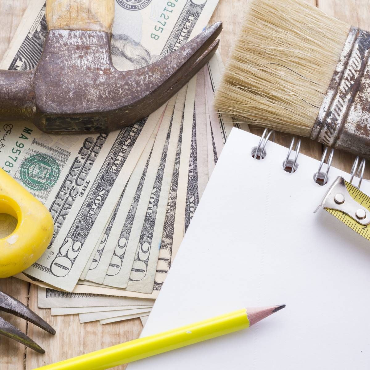 A hammer sits on top of a stack of 20 dollar bills