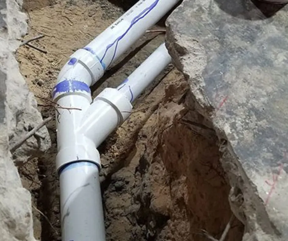 Plastic pipes and fittings installed in a rocky trench during excavation work