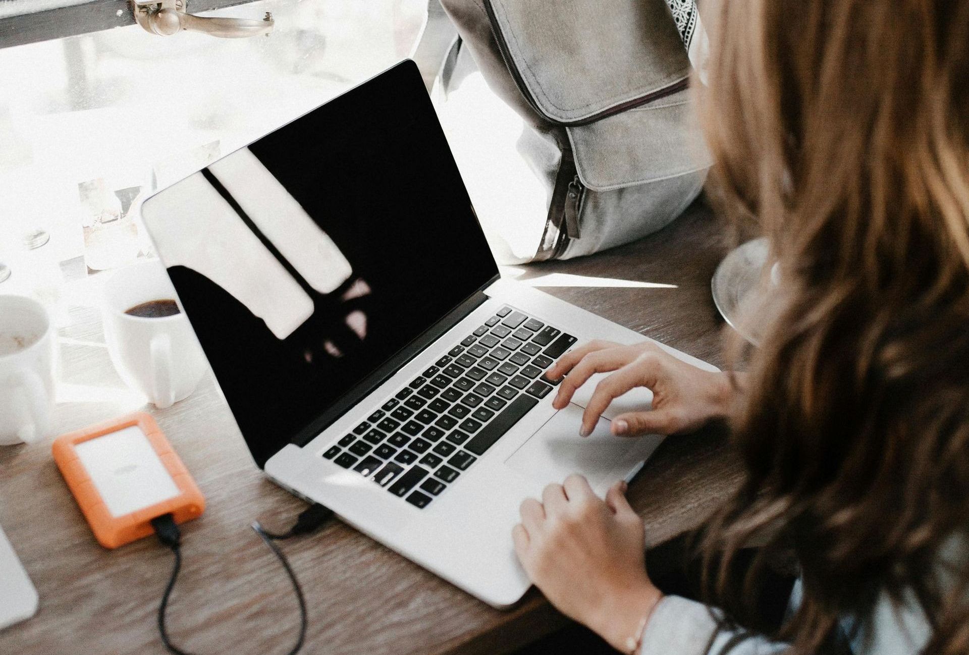 A woman is sitting at a desk using a laptop computer for content creation