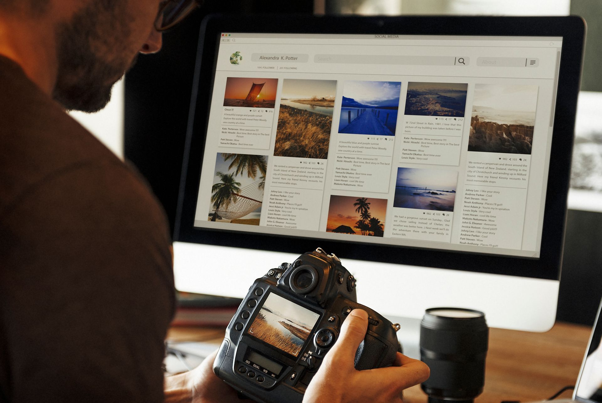 A man is holding a camera in front of a computer screen.