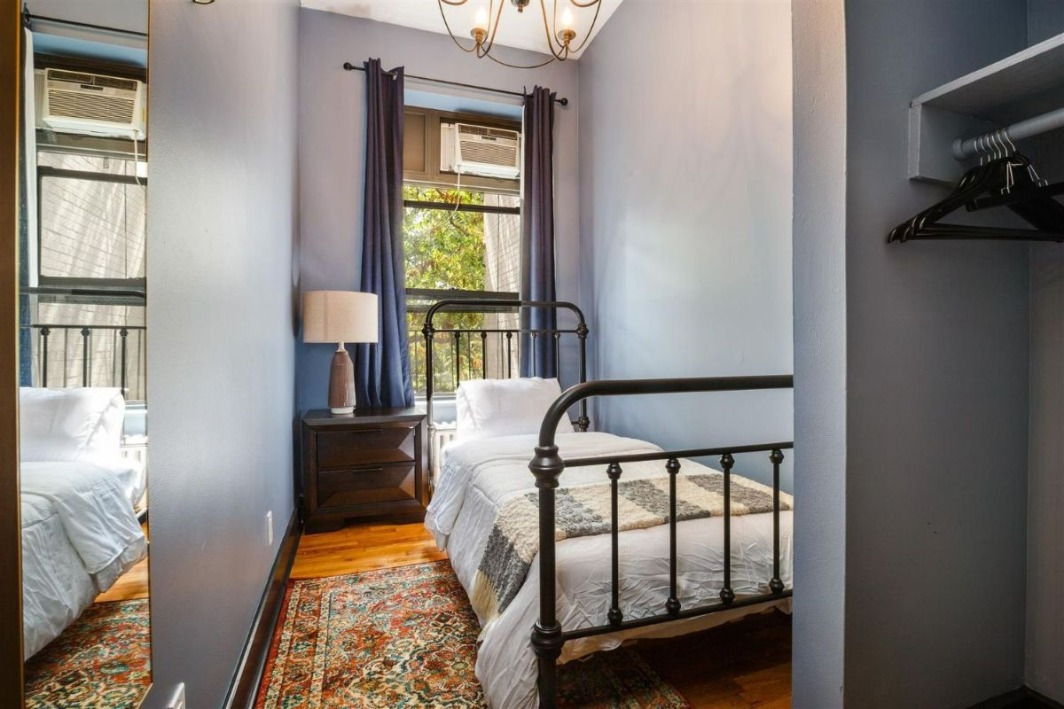 a bedroom with a single bed , nightstand , lamp and window .