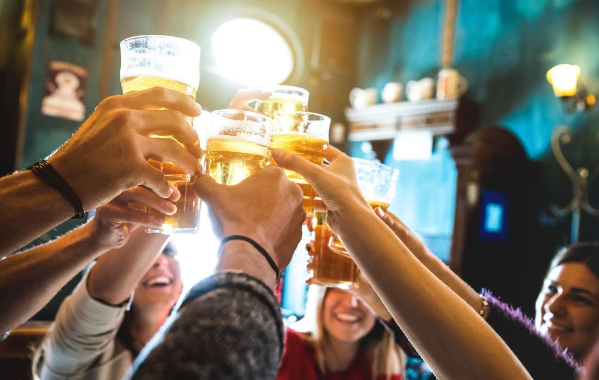 a group of people are toasting with beer glasses in a bar .