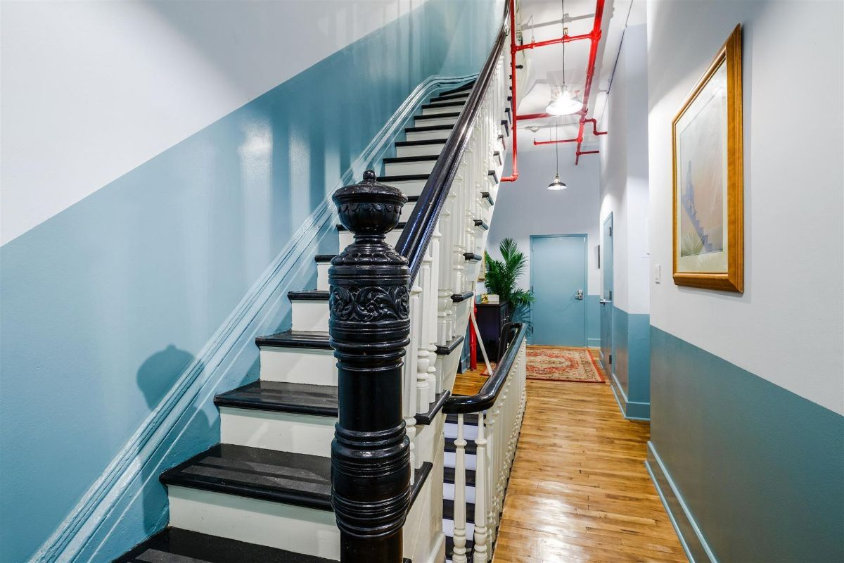 a long hallway with stairs and a picture on the wall .