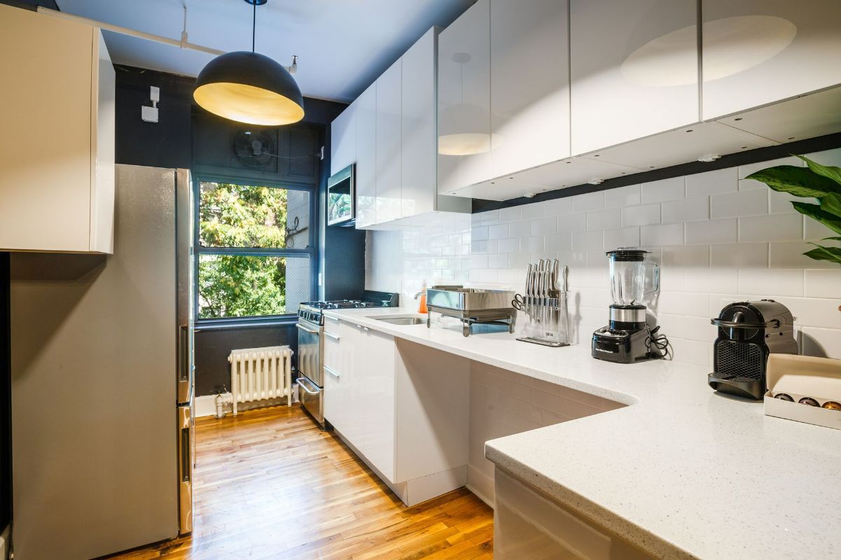 a kitchen with white cabinets , a refrigerator , a toaster oven , and a coffee maker .