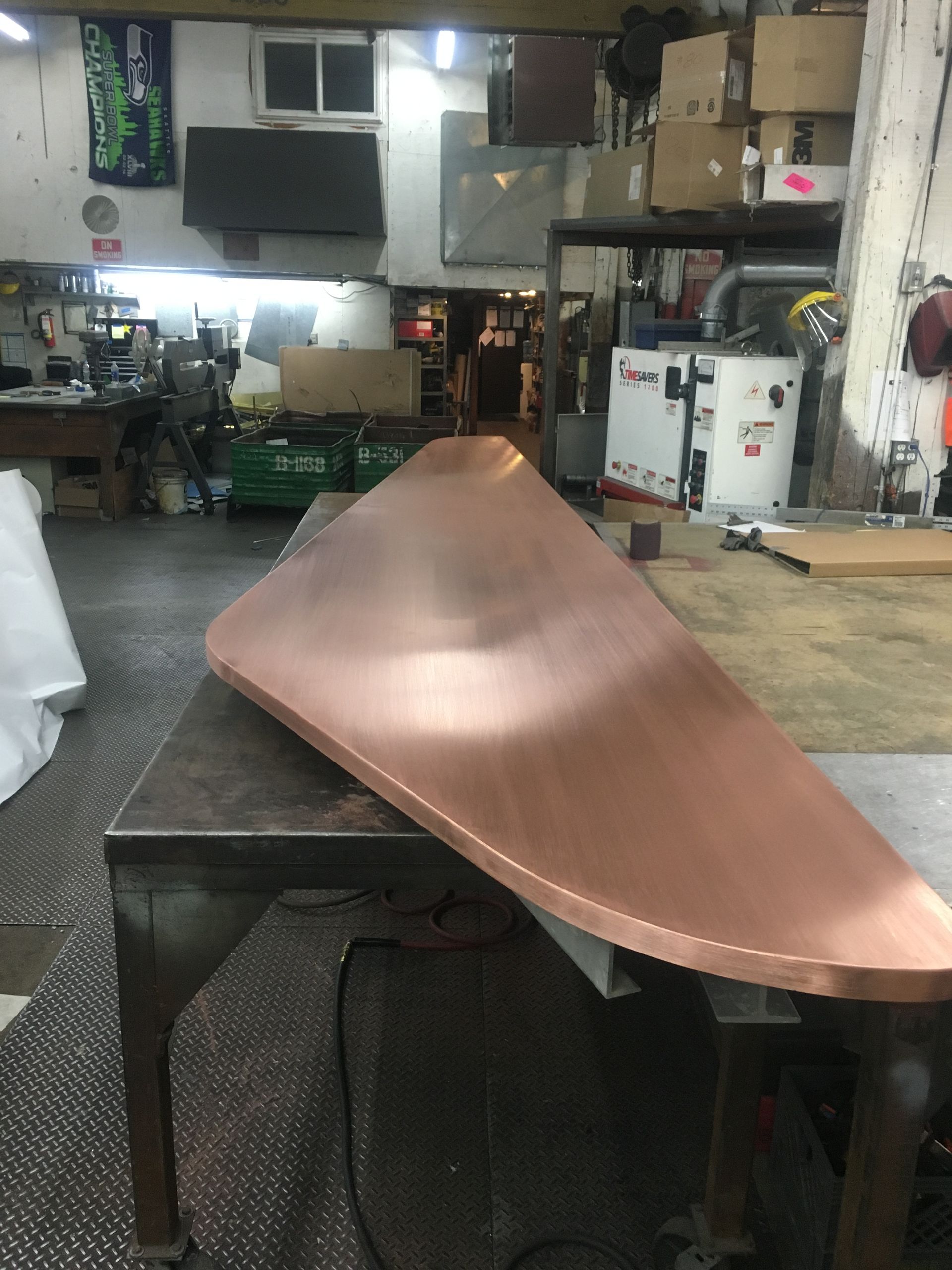 Copper metal piece on a workbench in a workshop.