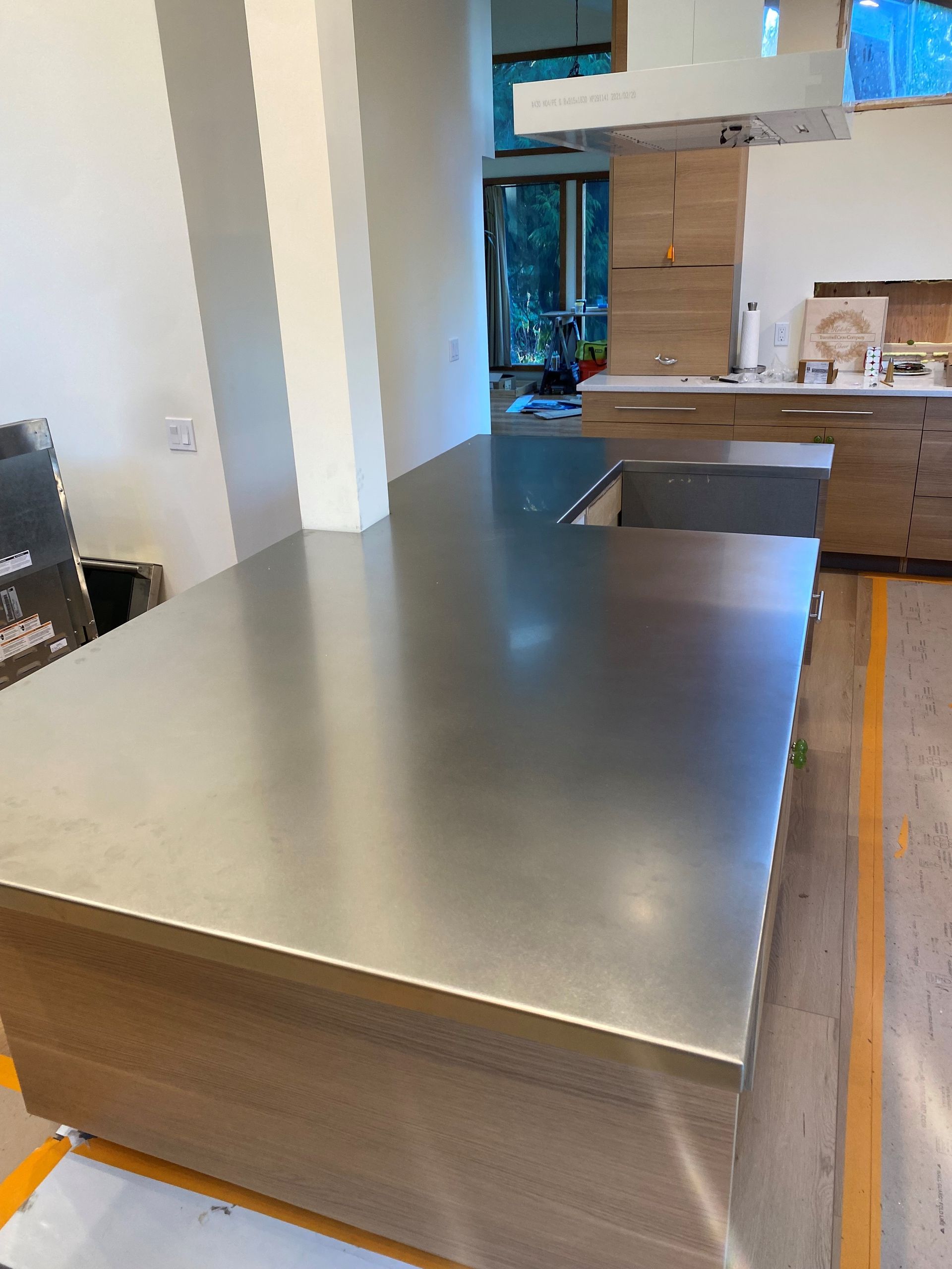 Stainless steel countertop on a wood kitchen island with a neutral color scheme.